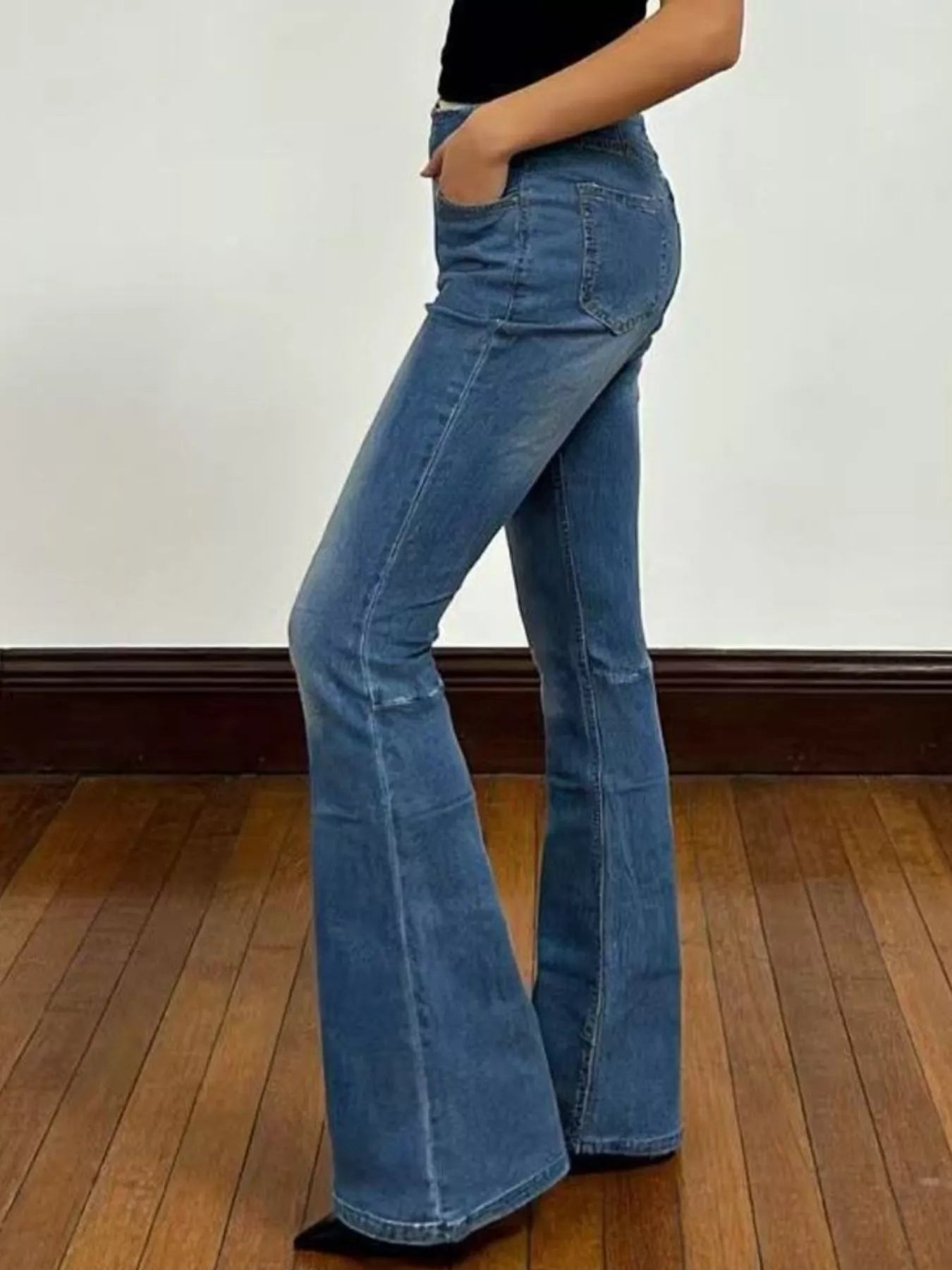 Model wearing High-Waisted Flare Jeans showcasing their stylish fit and flared design on wooden floor.