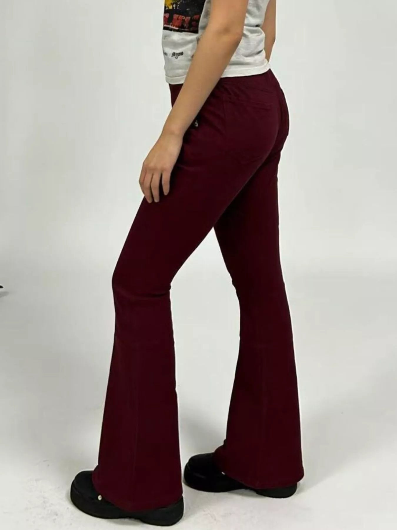 Side view of a model wearing High-Waisted Flare Jeans in burgundy with a fitted top.