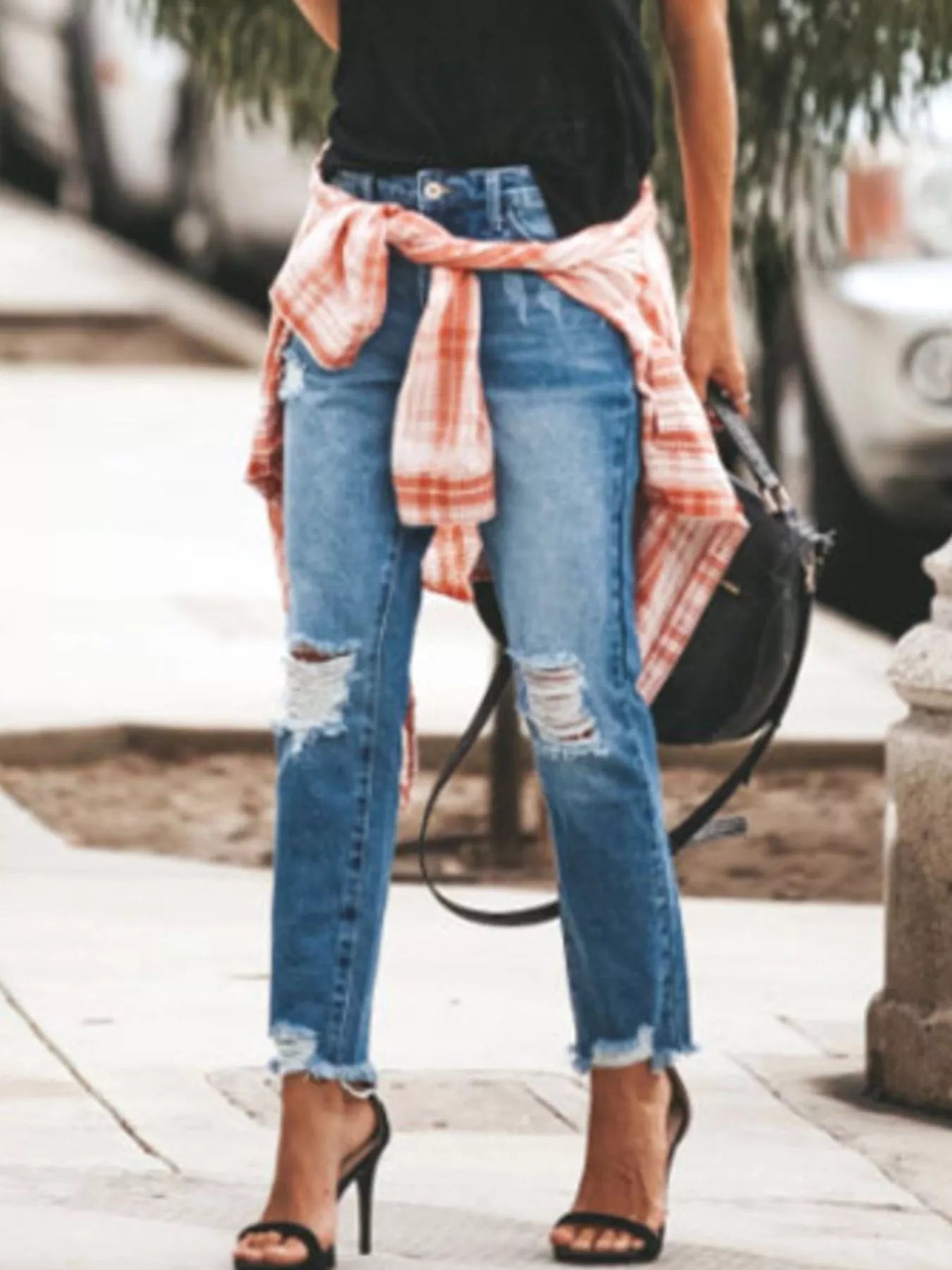 Distressed Wash Ankle Jeans with raw hem, styled with a plaid shirt and heels on a city street.