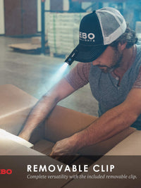Man using NEBO flashlight with removable clip, showcasing versatility in a dimly lit workspace.