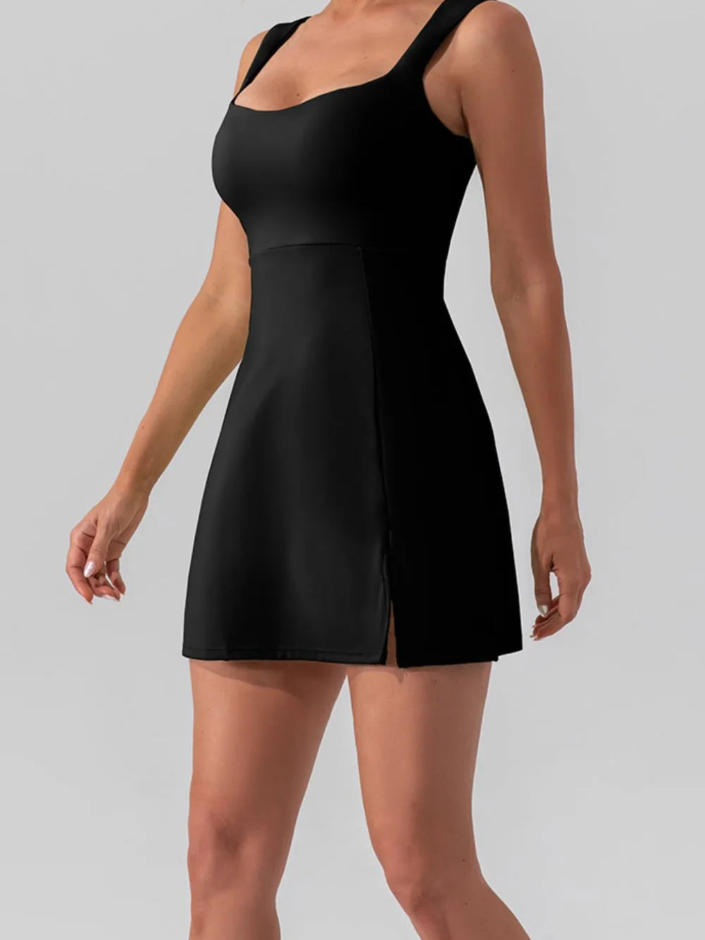 Model wearing a Square Neck Sleeveless Slit Mini Active Dress in black, showcasing its sleek design and stylish slit.