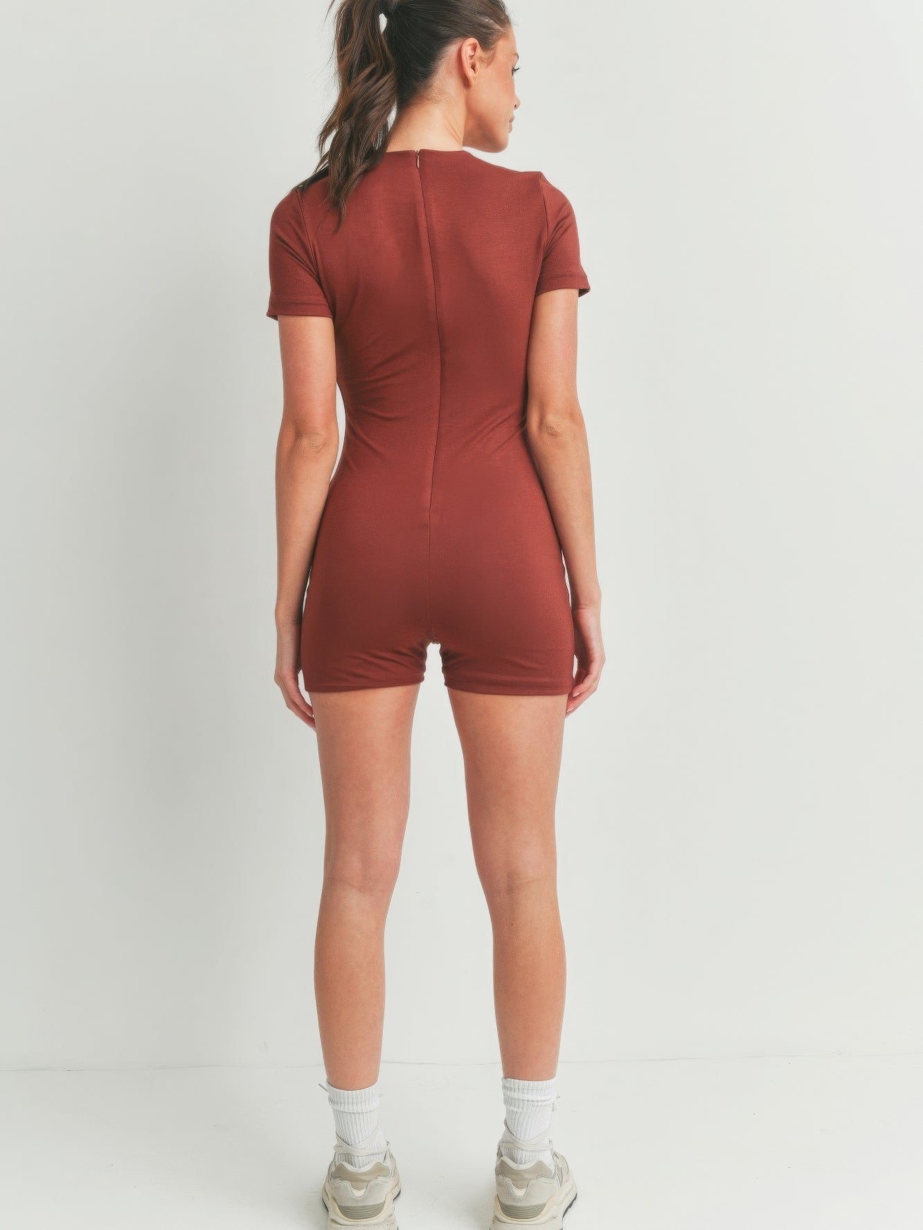 Model showcasing the back view of a Solid Color Bodycon Jumpsuit in brown, highlighting its flattering fit.