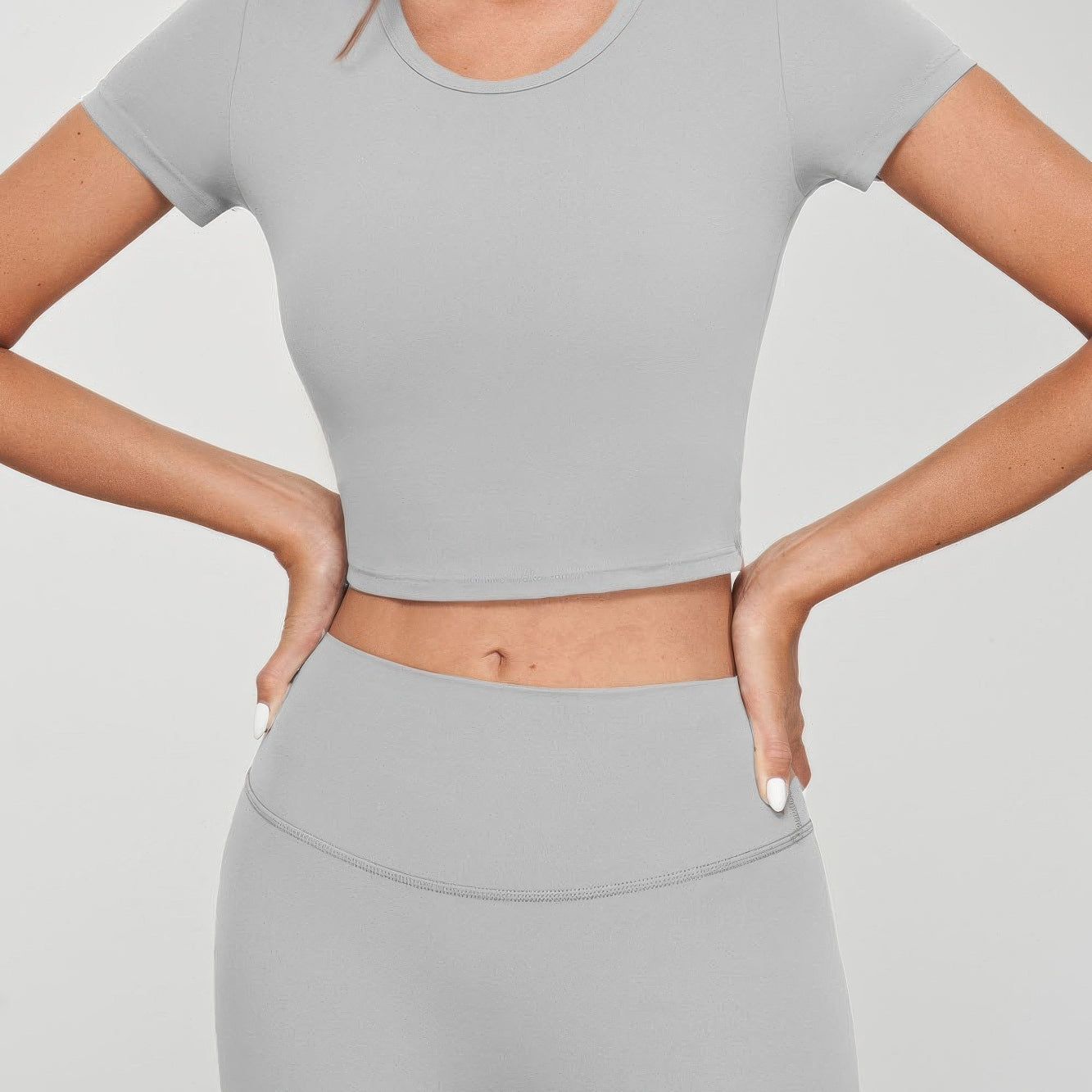 Model wearing a grey seamless crop tee with short sleeves and matching high-waisted bottoms.