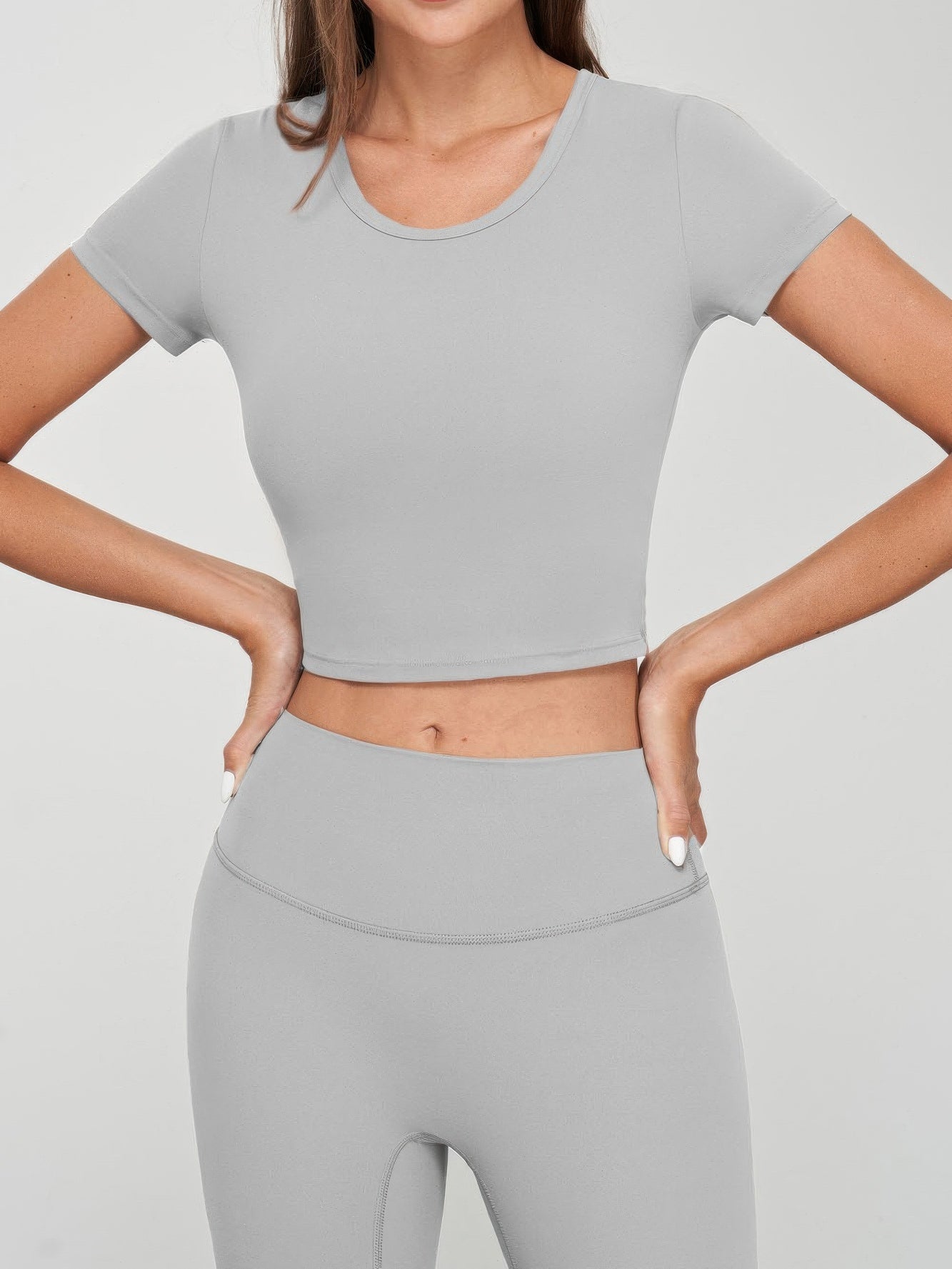Model wearing a grey seamless crop tee with short sleeves and matching high-waisted bottoms.