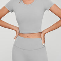 Model wearing a grey seamless crop tee with short sleeves and matching high-waisted bottoms.