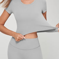Woman demonstrating the fit of a seamless crop tee in grey, showcasing its comfort and flexibility.