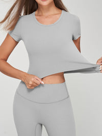 Woman demonstrating the fit of a seamless crop tee in grey, showcasing its comfort and flexibility.