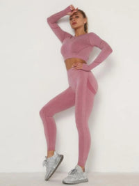 Model in pink seamless activewear set, showcasing long sleeves crop top and high-waisted leggings for stylish performance.
