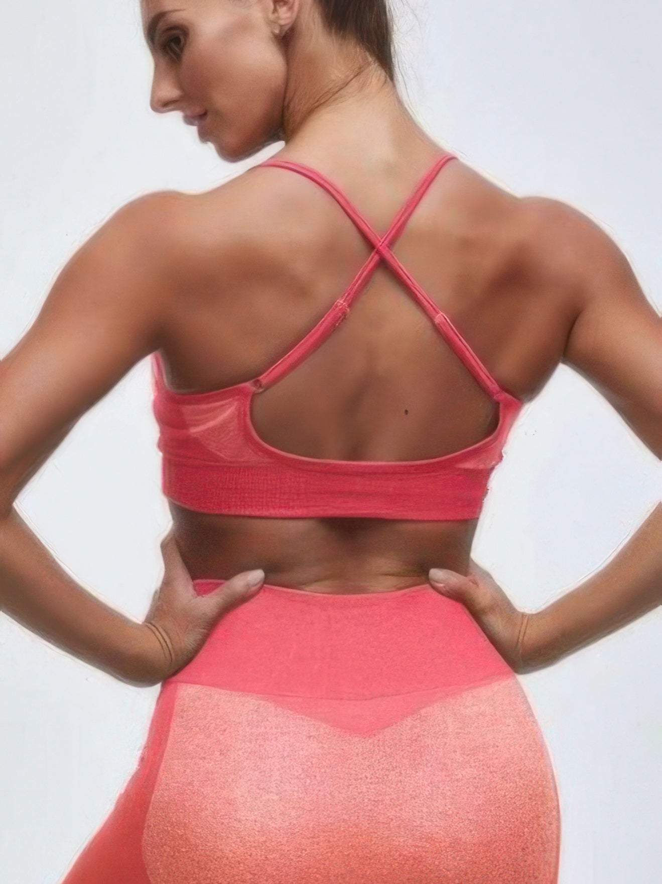 Back view of a model wearing a seamless activewear two piece set in vibrant pink.