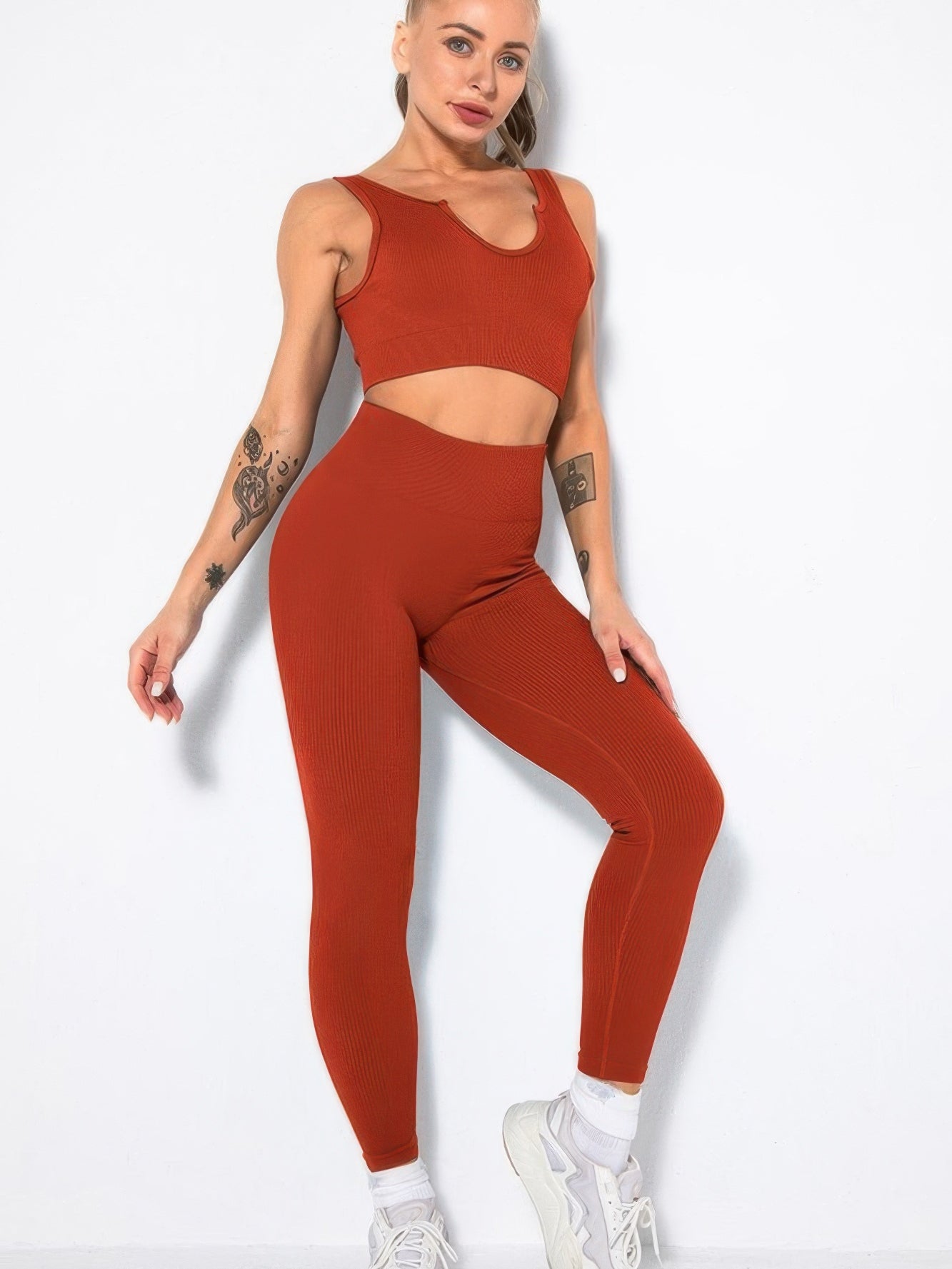 Ribbed two piece activewear set featuring a sleeveless crop top and high-waisted leggings in a rich rust color.