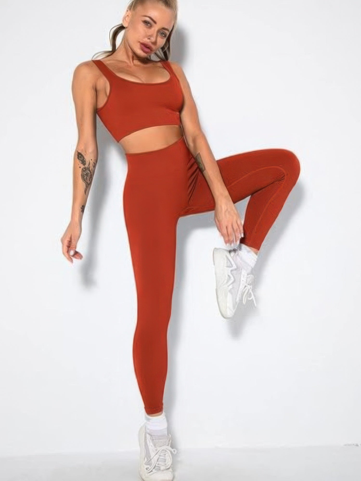 Model wearing a ribbed two piece activewear set in orange, featuring a crop top and high-waisted leggings.