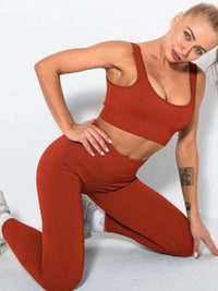 Model showcasing ribbed two piece activewear set in rust color, featuring sleeveless crop top and high-waisted leggings.