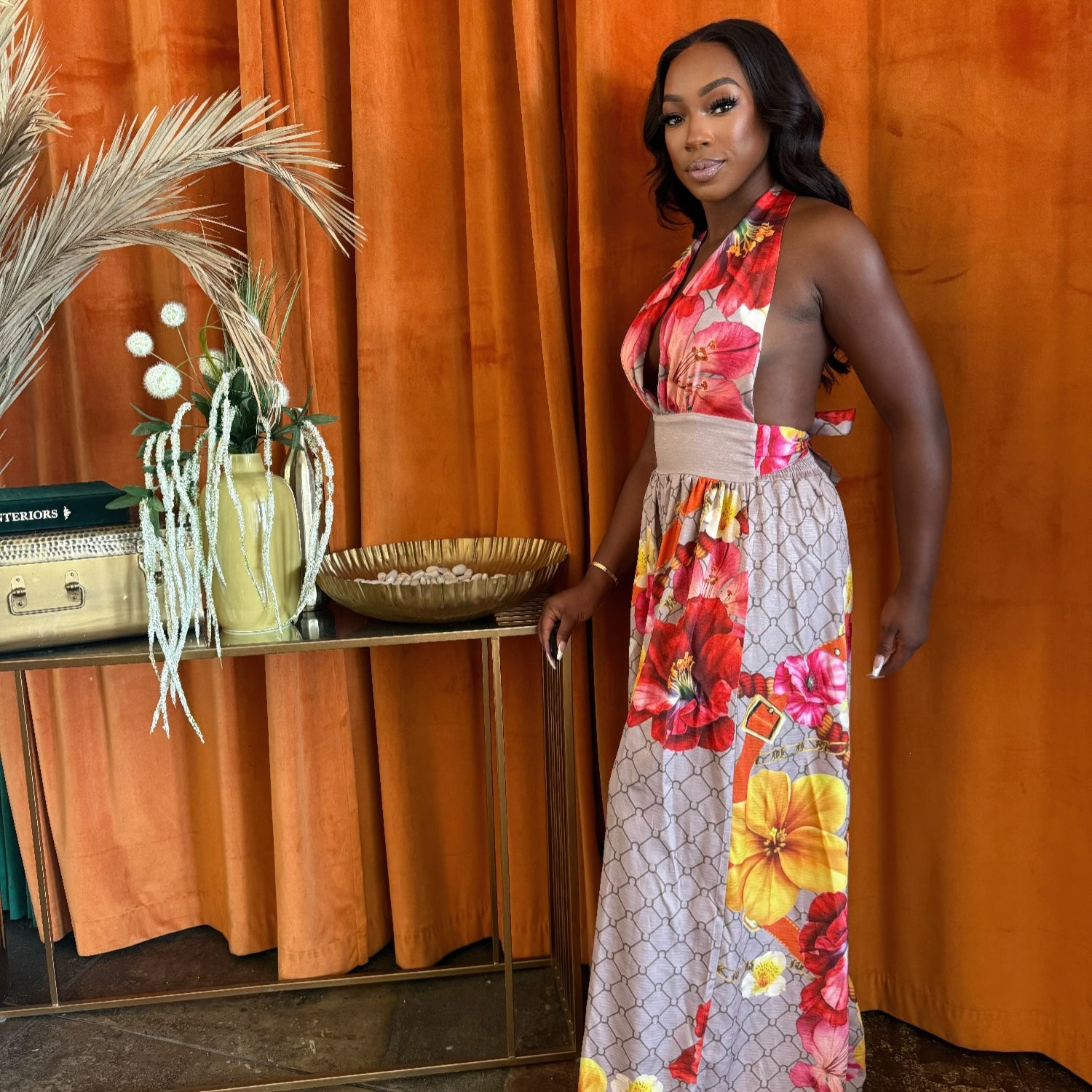 Model wearing the Paradise Bloom Jumpsuit, a resort style jumpsuit with floral patterns and a plunging neckline.