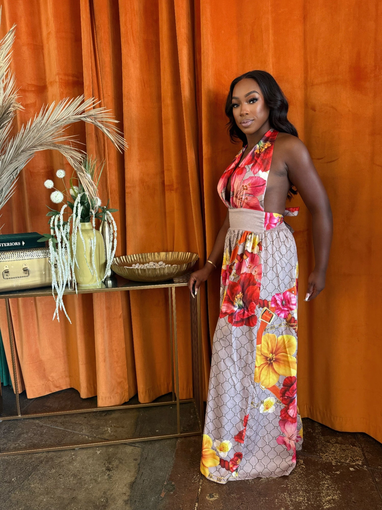 Model wearing the Paradise Bloom Jumpsuit, a resort style jumpsuit with floral patterns and a plunging neckline.