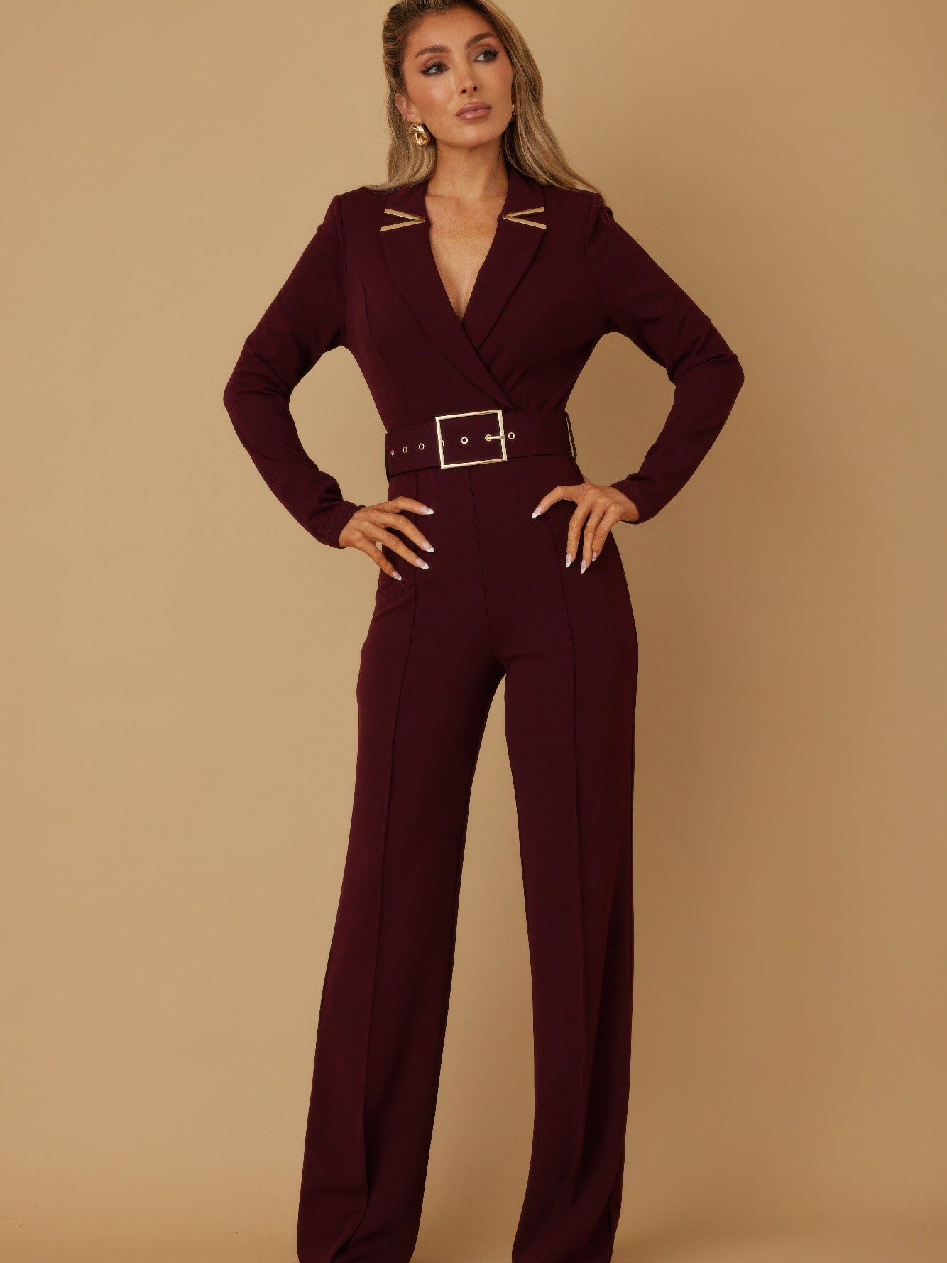 Stylish woman wearing a blazer jumpsuit for women with belt and long sleeves in a burgundy color.