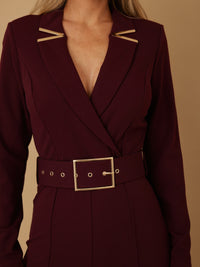 Woman wearing a burgundy blazer jumpsuit for women with long sleeves and a cinched waist.