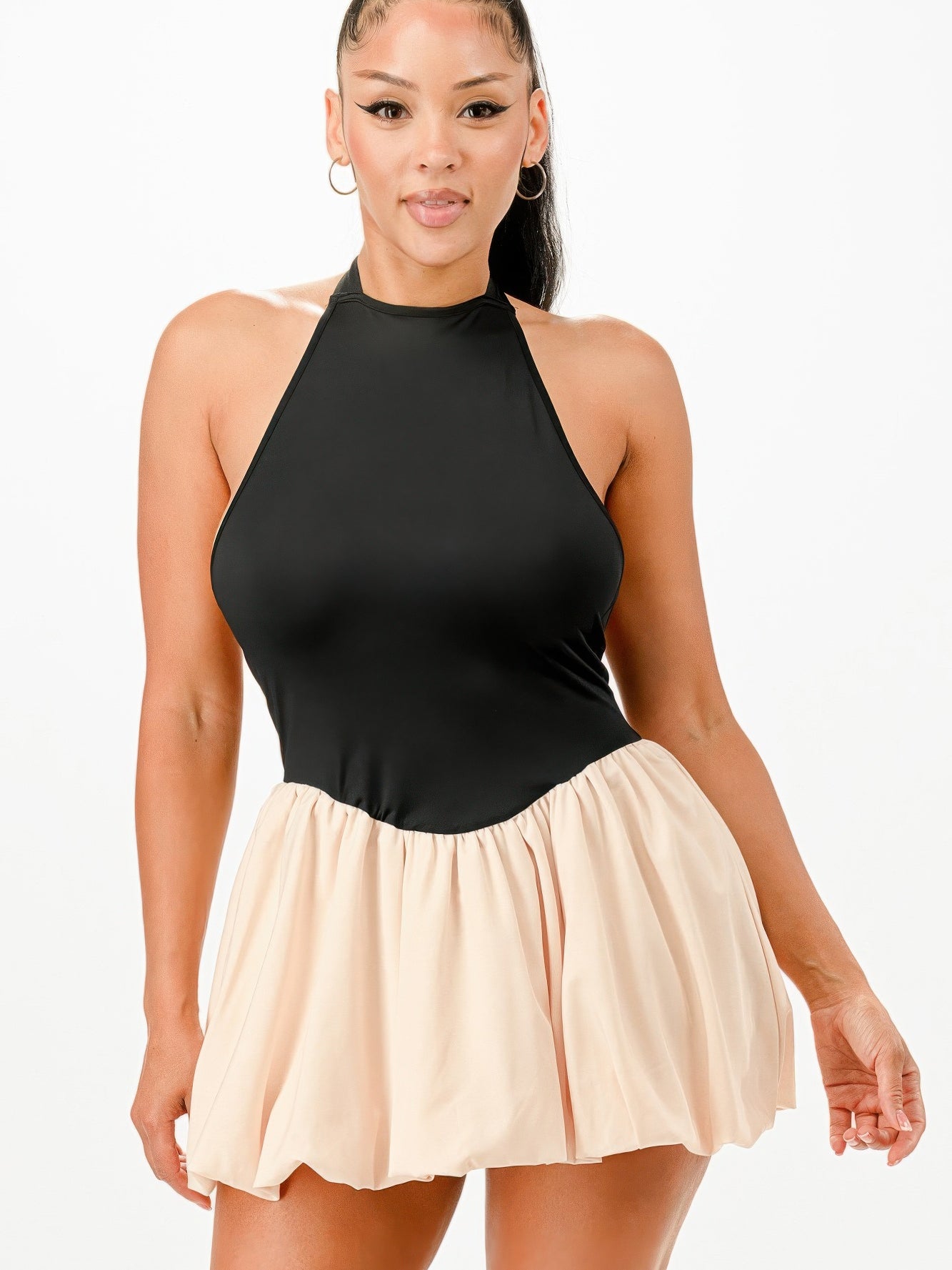 Model wearing a Bubble Mini Dress featuring a halter neckline and a bubble skirt in classic black and beige.