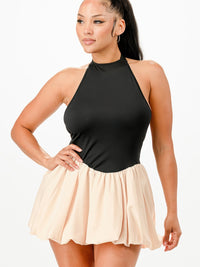 Model wearing a Bubble Mini Dress featuring a halter neckline and flared skirt in black and nude.