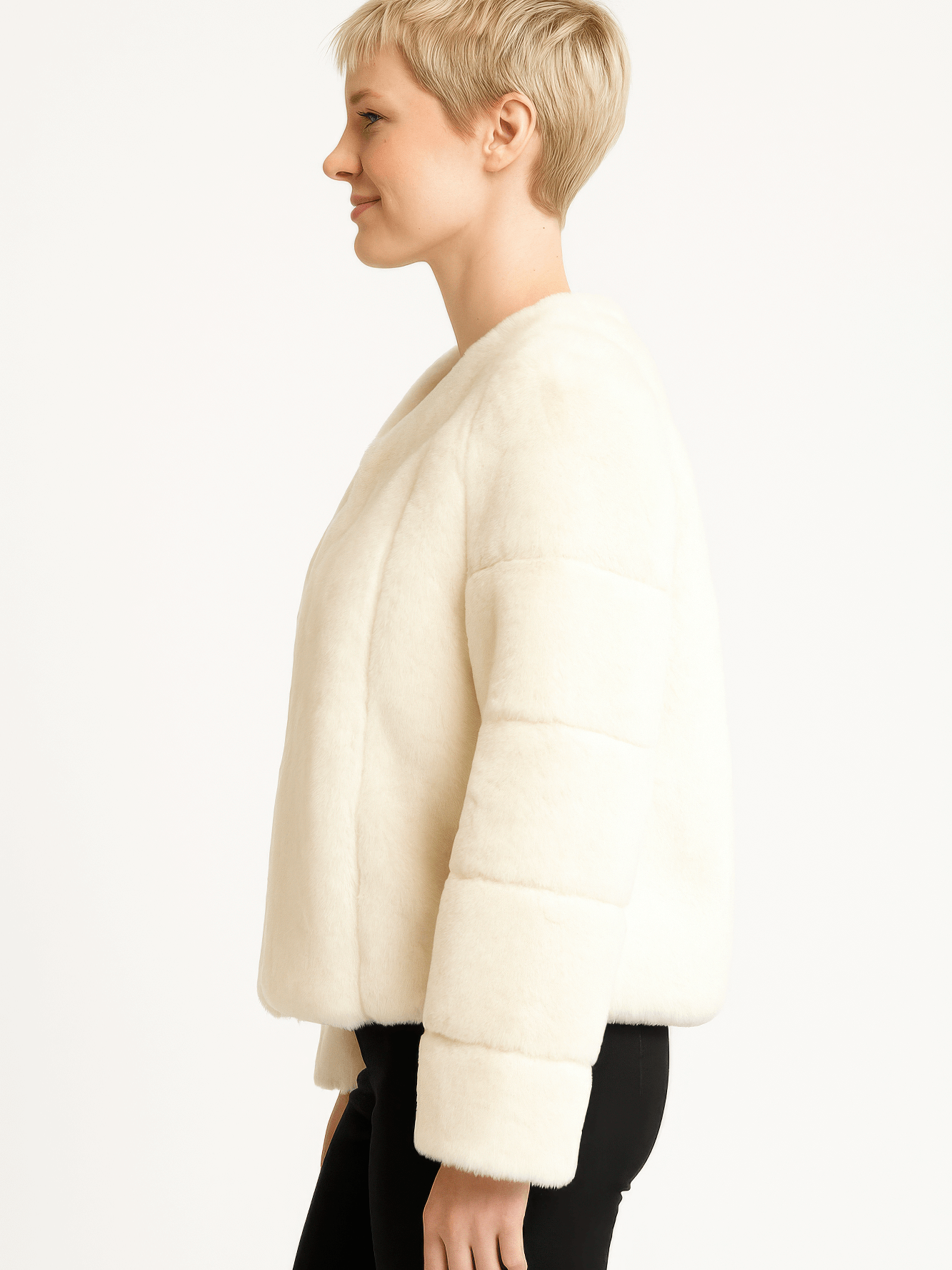 Side view of a woman wearing a cozy, ivory faux fur jacket with a relaxed fit and long sleeves.