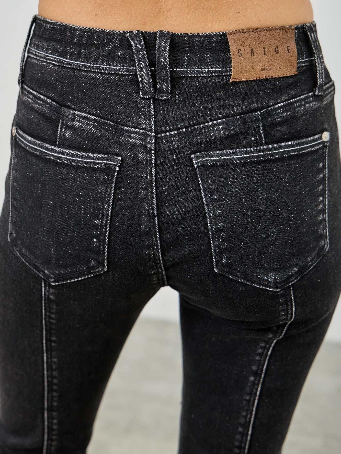 Close-up of mid rise slim straight jeans in black acid wash showing back view and pocket details.