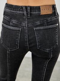 Close-up of mid rise slim straight jeans in black acid wash showing back view and pocket details.