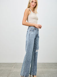 Model showcasing Mid Rise Relaxed Straight With Destroy jeans with a beige tank top and heels.