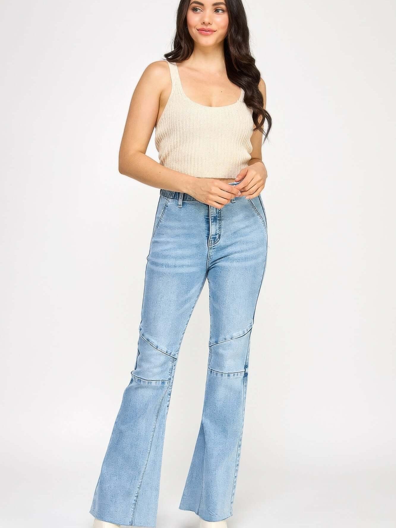 High Rise Flare With Seam Detail model wearing light blue jeans with a soft, fitted tank top.