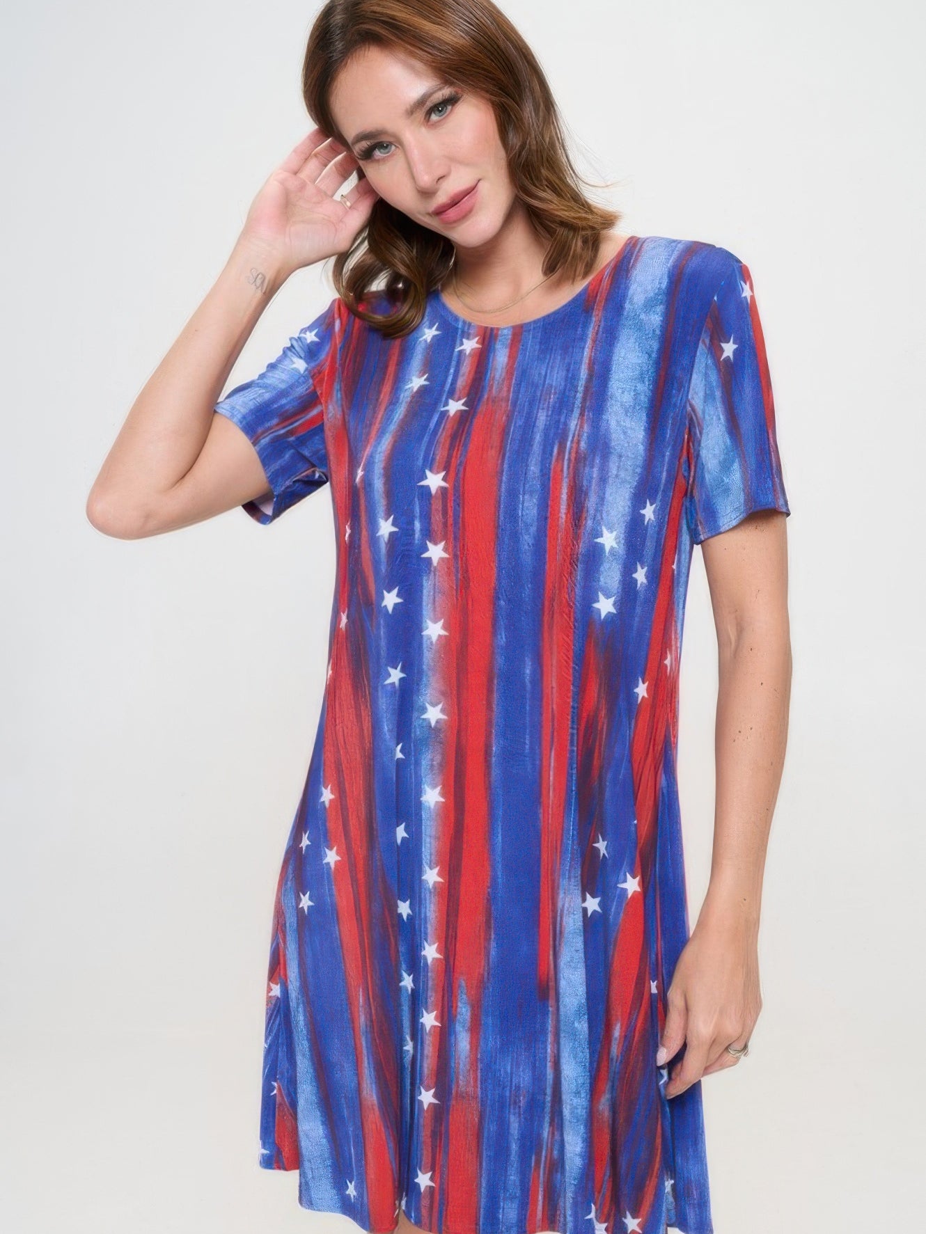 Model wearing a short-sleeved knee-length dress with red, blue, and star pattern against a light background.