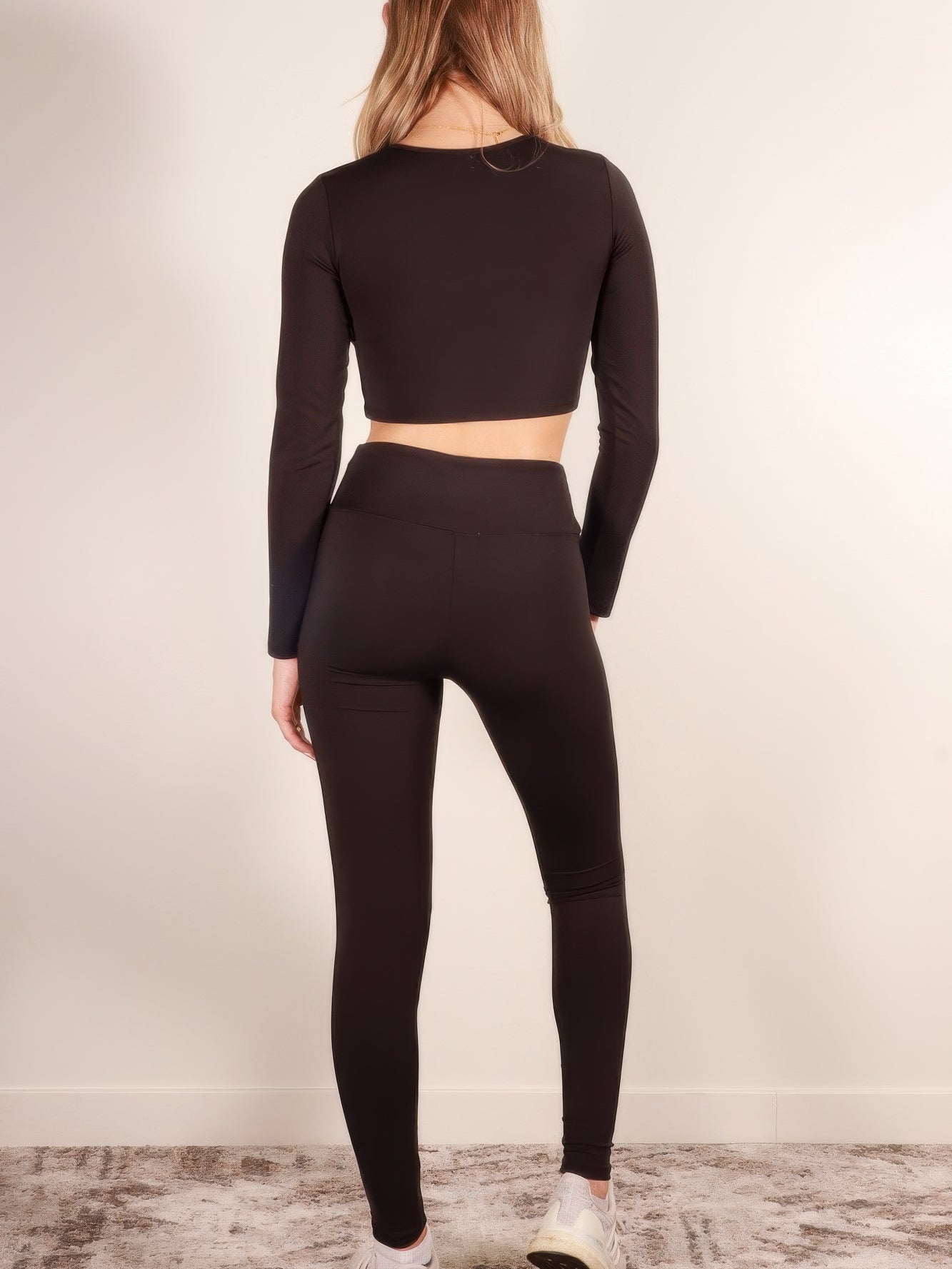 Back view of long sleeve crop top and leggings activewear set in black, showcasing smooth fabric and sleek fit.