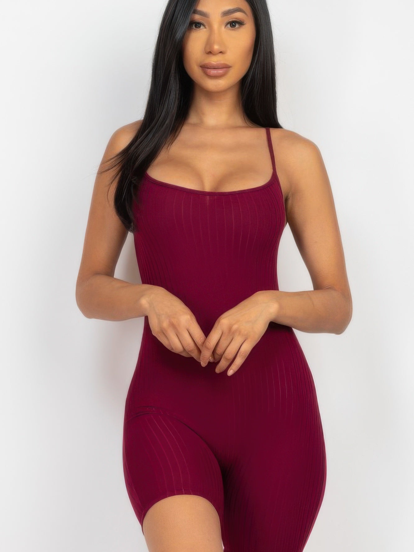 Model wearing ribbed bodycon romper in burgundy, featuring spaghetti straps and a fitted mini biker short design.