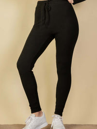 Ribbed tie front lounge leggings in black displayed on model with white sneakers.