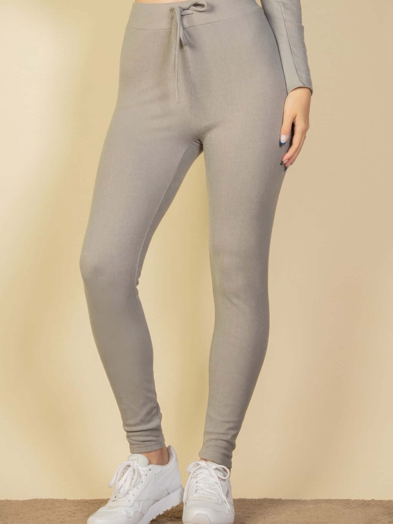 Model wearing ribbed tie front lounge leggings in light gray, paired with white sneakers.