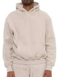 Model wearing a unisex premium cotton blend hoodie in light beige, showcasing relaxed fit and comfort.