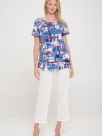 Round neck short sleeve top with a colorful abstract design, paired with white pants for a chic casual look.