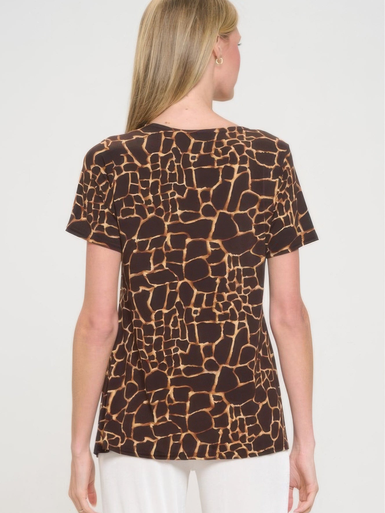 Back view of a woman wearing a short sleeve slit top with a giraffe print design.