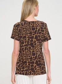 Back view of a woman wearing a short sleeve slit top with a giraffe print design.