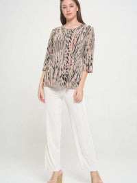 Model showcasing the Print Hit Merrow Top, featuring elegant designs paired with stylish white pants.