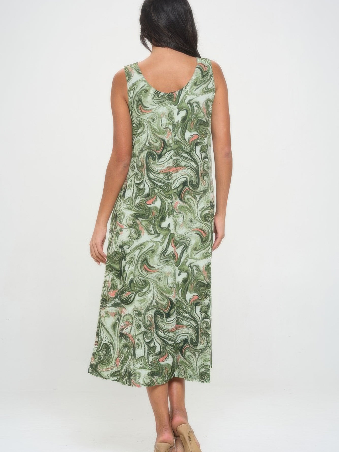 Back view of a woman wearing a printed long tank dress with a green and white swirl pattern.