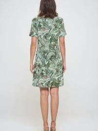 Back view of a woman wearing a plus size print missy dress with a green abstract print short sleeves.