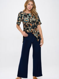 Woman wearing Elastic Waistband Flared Pants with floral tunic top on a white background.