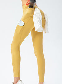 Full Size Slim Fit High Waist Long Sports Pants with Pockets in yellow, showcasing pockets and flexibility for active wear.