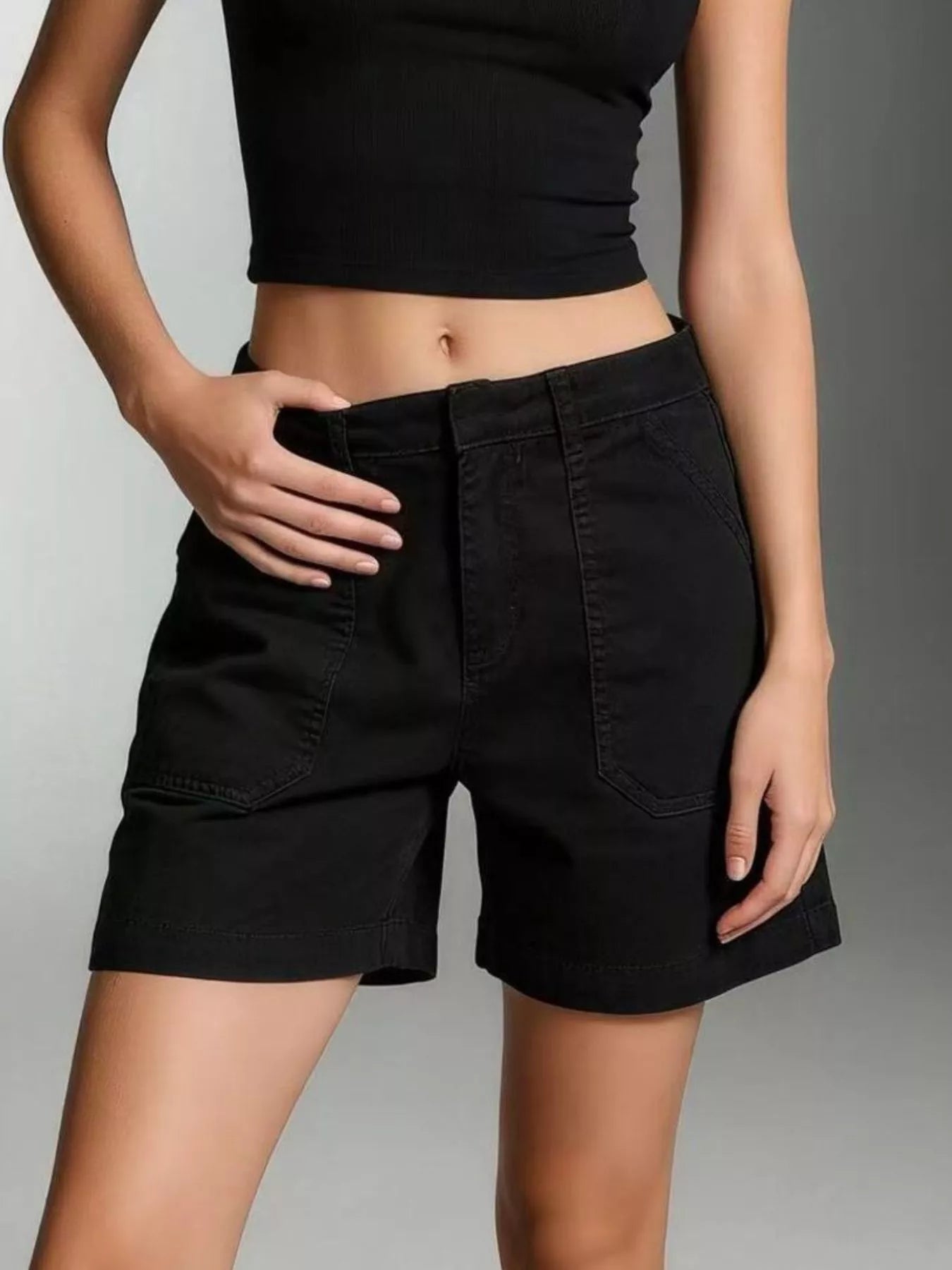 Model wearing Pocketed Denim Shorts, featuring a black color, front pockets, and a buttoned design.