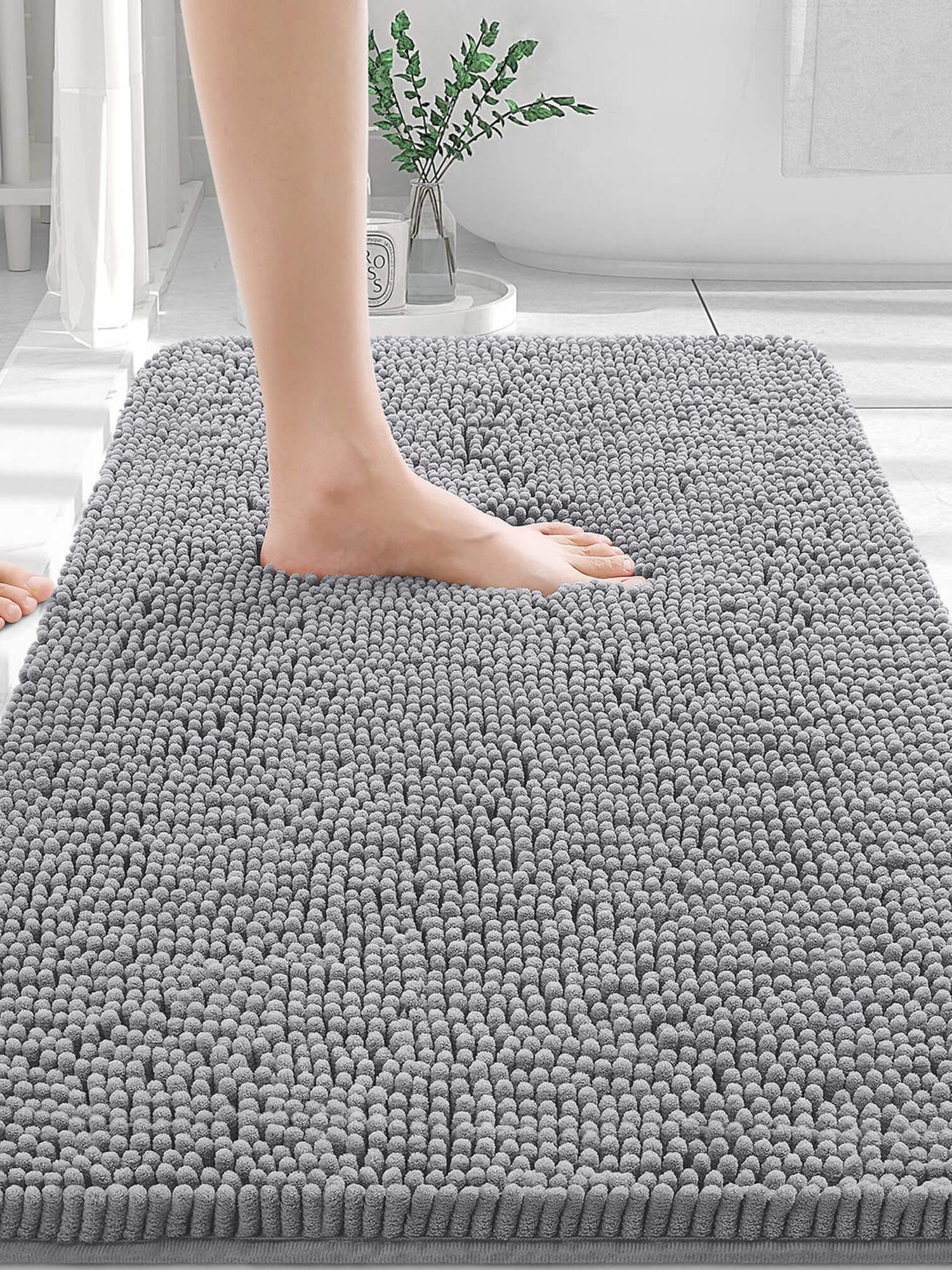 Person stepping onto a soft grey OLANLY bathroom rug, featuring plush chenille texture for comfort and absorbency.