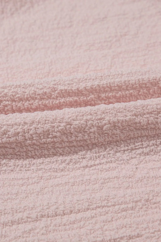 Textured Bow Knot Frilled Butterfly Sleeve Blouse fabric close-up, soft pink material with woven texture.