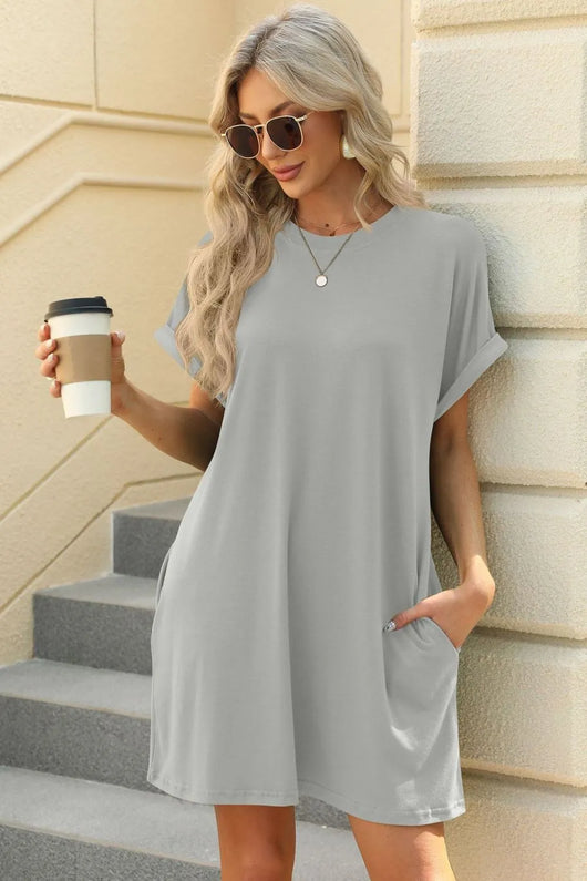 Florira Short Sleeve Mini Dress with Pockets modeled by a woman holding coffee in a casual gray outfit.