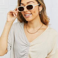 Oval Full Rim Sunglasses showcased by a woman wearing a stylish outfit and smiling.