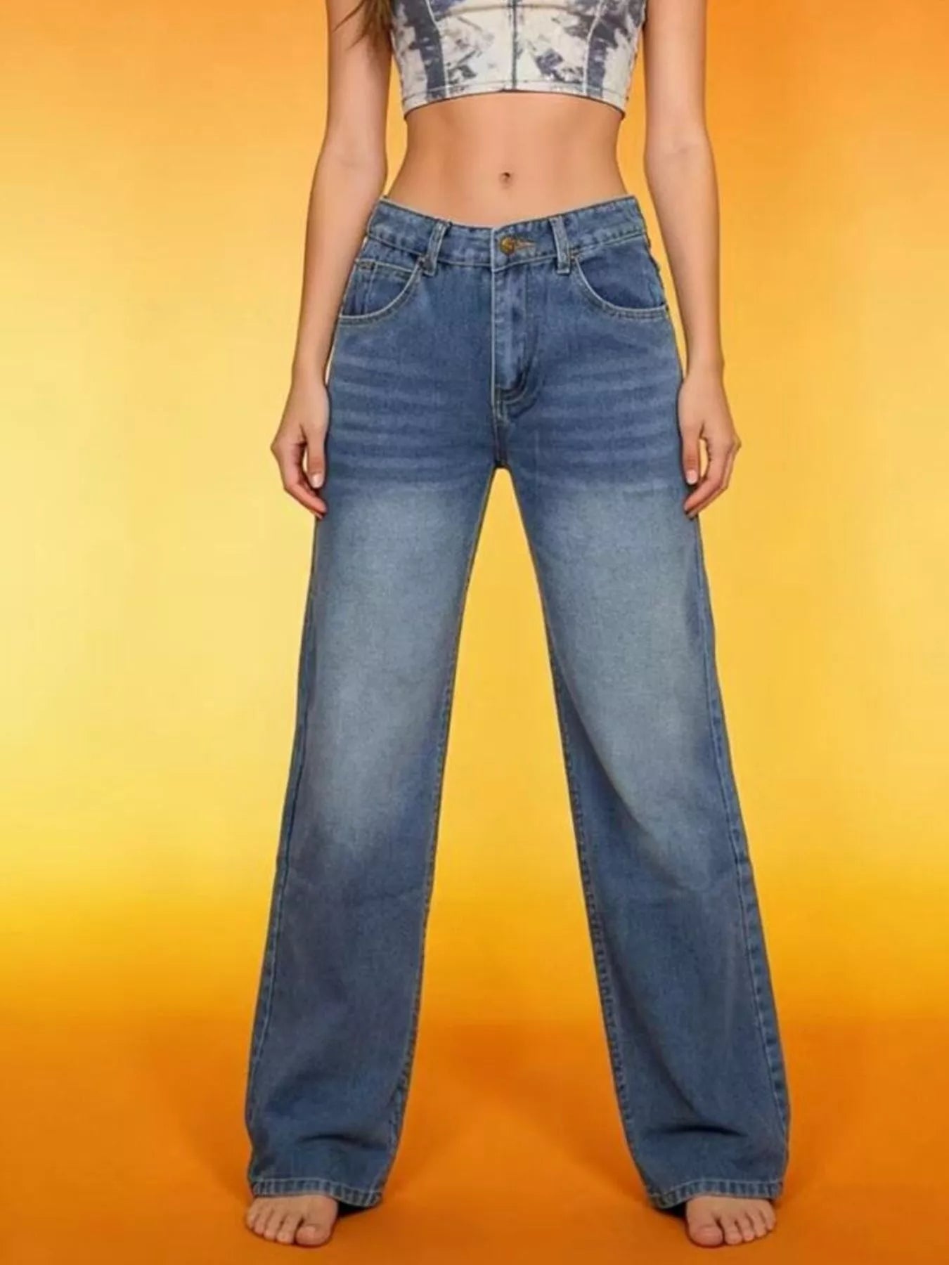 Model showcasing Vintage Wash Wide Leg Jeans against a vibrant orange background.