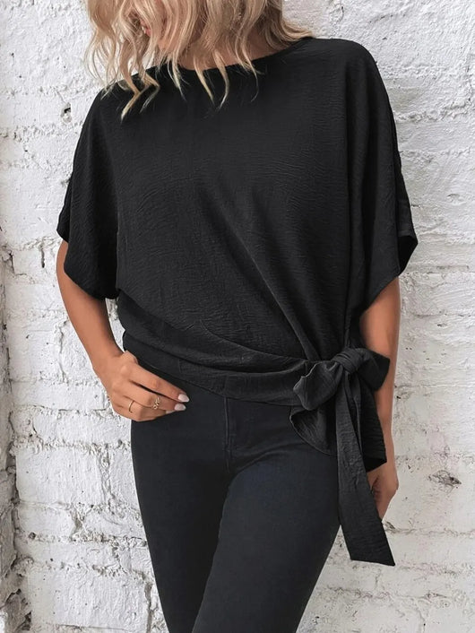 Knotted Round Neck Half Sleeve Blouse showcasing a tied waist detail, styled with black skinny jeans.