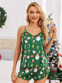 Woman in green silk pajamas with Christmas print, featuring Santa, candy canes, and gifts, posing in a festive room.