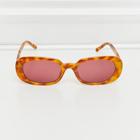 Oval Full Rim Sunglasses with orange tortoiseshell frame and pink lenses on a white background.